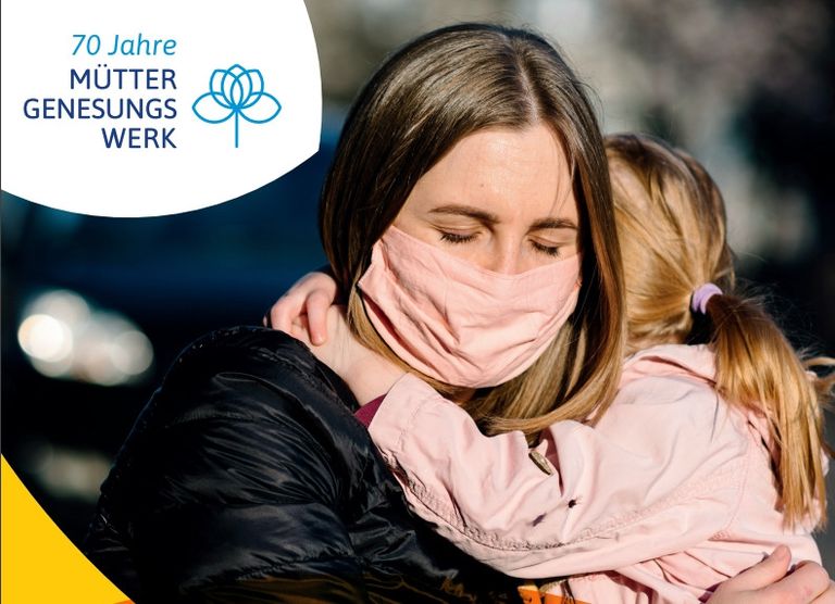 Mutter und Kind umarmen sich herzlich mit Maske, 70 Jahre Muttergenesungswerk-Jubiläum.